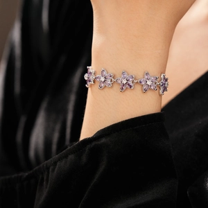 Makroaufnahme des silbernen Blumenarmbands mit violetten Zirkonia-Blüten am Handgelenk