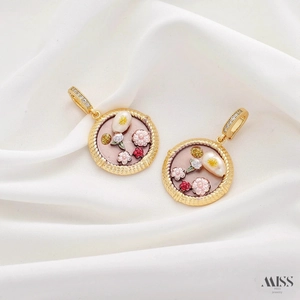 Detailed close-up of vintage flower charms with pink enamel and pearls on white silk