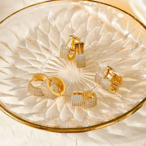 Luxe gold huggie earrings with micro-paved zircons in a textured glass dish