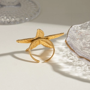 Detail of adjustable gold starfish ring with textured granules on glass tray