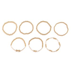Macro view of 7-piece set featuring gold beaded rings and wire design on white background