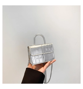 Detail of silver embossed mini square bag with crocodile pattern and chain strap
