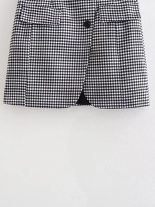 Détail d'une jupe en tweed pied-de-poule avec poche à rabat et bouton noir élégant
