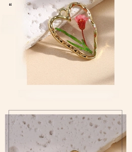Close-up of heart-shaped gold resin pendant with red dried flowers and shimmer