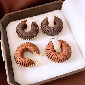 Créoles rétro en cuir tressé avec fermoirs en métal doré dans une boîte à bijoux