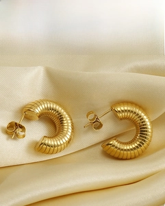 Nahaufnahme von vergoldeten Edelstahl-Creolen mit spiralförmigem Wellendesign für Damen