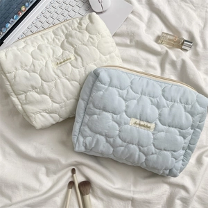 Detailed close-up of quilted cloud pattern makeup bags in beige and light blue colors