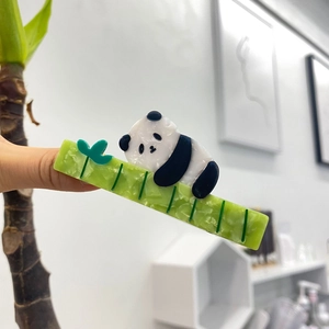 Detailed view of panda hair claw clip with green bamboo pattern and acetate texture