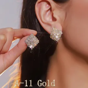 Close-up of sparkling square rhinestone stud earrings in a gold finish on ear