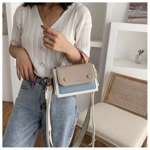 Detail of color-block patchwork shoulder bag with dual round buckles and wide strap