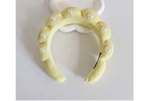 Close-up of pale yellow plush headband featuring bubble texture and pearl embellishments