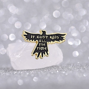 Eagle wing enamel brooch with 'IT CAN'T RAIN ALL THE TIME' quote on white stone