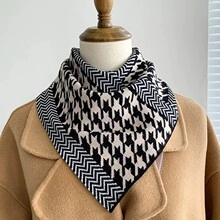 Detail of black and white houndstooth knit neck warmer paired with a camel coat