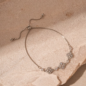 Gros plan de charms trèfle en zircon sur un bracelet coulissant en argent poli