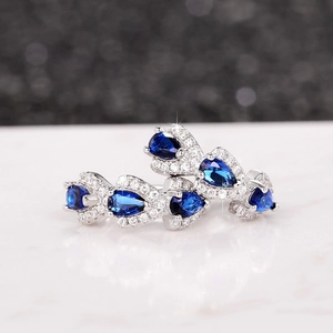 Detailed macro view of pear-cut deep blue sapphire earrings with cubic zirconia halo