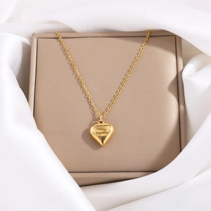 Elegant gold heart pendant necklace with romantic engraving on soft satin background