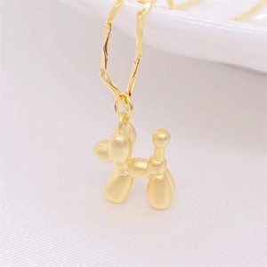 Detailed macro view of the gold-plated balloon dog pendant on white fabric texture