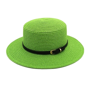 Detailed view of the vibrant green woven straw hat featuring a flat top and black belted strap