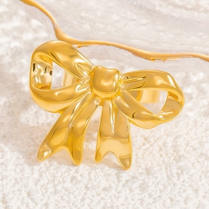 Elegant gold bow ring in stainless steel with a polished metallic finish on a white stone base