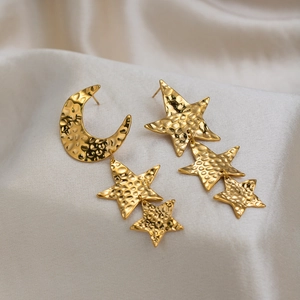 Macro detail of 18K gold plated stainless steel asymmetric moon and star earrings with hammered finish