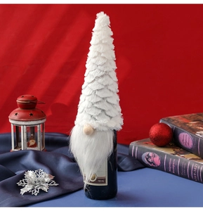 Detail of white plush gnome wine bottle cover with tiered hat on festive red background