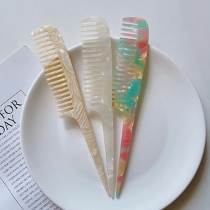 Three marble pattern acetate tail combs on a white tray for hairstyling and parting