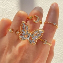 Detail of stacked gold rings featuring butterfly, moon and star charms with zircons