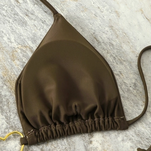 Macro view of olive brown bikini cup with golden heart metal ring and pleated fabric detail