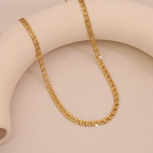 Layered gold snake bone Cuban chain necklace displayed on a minimalist jewelry stand