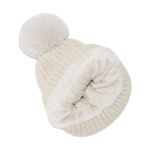 Détail d'un bonnet d'hiver en maille beige avec doublure polaire blanche et pompon doux