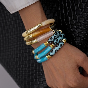 Detail of bohemian acrylic and gold beaded stretch bracelets on model wrist