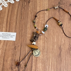Detail einer Boho-Halskette mit Holzhalbmond und Bronze-Anhänger auf Holzhintergrund