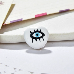 Detailed macro view of heart-shaped evil eye beads for DIY jewelry making on a tray