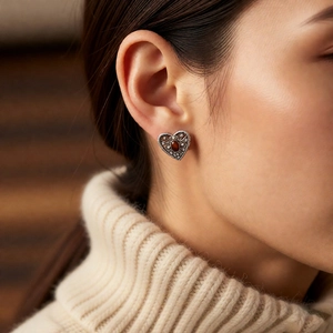 Close-up of vintage hollow heart earring featuring a red zircon and silver metal finish
