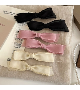 Close-up of 6-piece set of elegant bow hair clips in black, pink and beige fabric