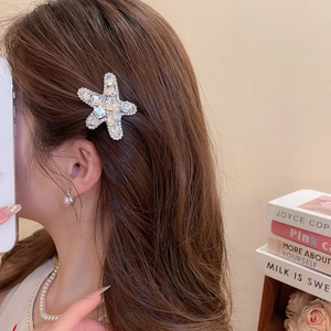 Close-up of sparkling rhinestone starfish hair clip on woman's side hair with elegant details