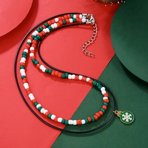 Detail of Christmas beaded necklace featuring a green snowflake charm and double layer cord