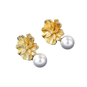 Elegant gold flower earrings with white pearls and zircons on a white background