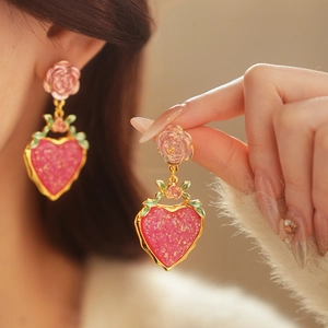 Macro detail of vintage pink rose and sparkling heart-shaped earring with golden trim