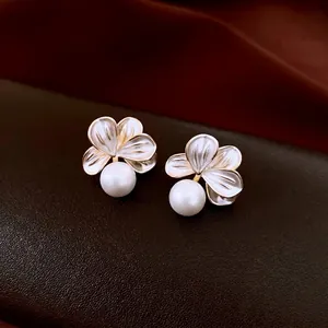 Elegant 18K gold plated flower pearl earrings with white petals on leather background