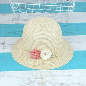 Détail d'un chapeau de paille beige orné de fleurs en tissu et d'un ruban en ficelle