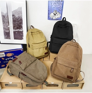 Four minimalist canvas backpacks in black, yellow, green and khaki on shoe boxes