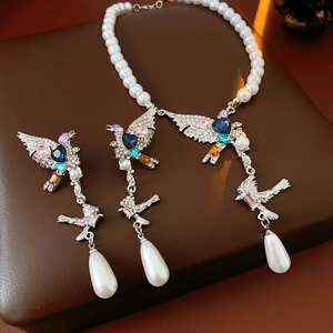 Détail macro de la parure oiseau avec pierres précieuses colorées et pendentifs perles