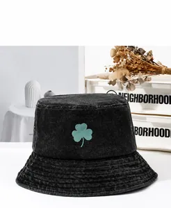 Vista detallada de un sombrero bucket de mezclilla negra con trébol verde bordado