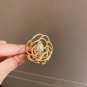 Detail of a vintage golden rose metal hair claw with a central pearl in hand display