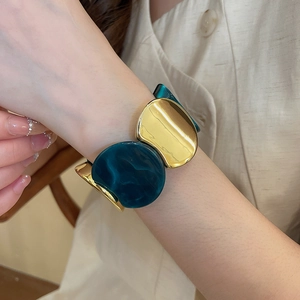 Détail d'un large bracelet avec métal doré et panneaux en résine marbre vert