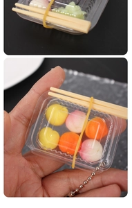 Close-up of a miniature dollhouse food box keychain with colorful fruit toy models inside