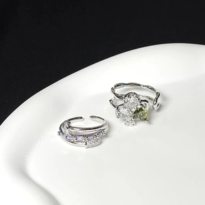 Detail of silver rings set featuring purple zircon layers and green heart stone