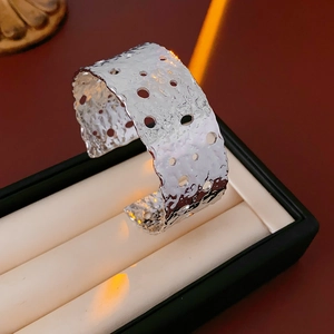 Macro detail of silver hammered finish wide cuff bracelet with artistic hollow cutouts
