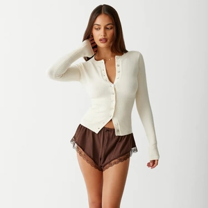 Detail of slim fit knit cardigan with V-neck button closure and lace trim shorts